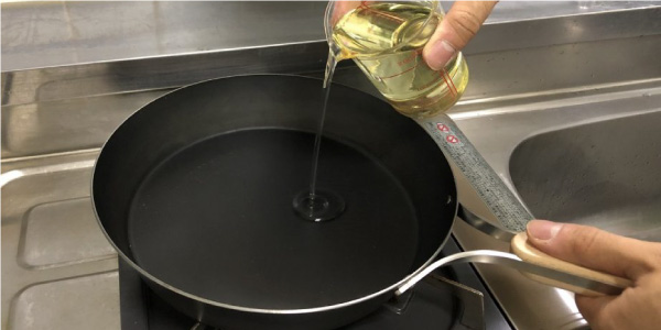 鉄フライパンに食用油を入れる作業