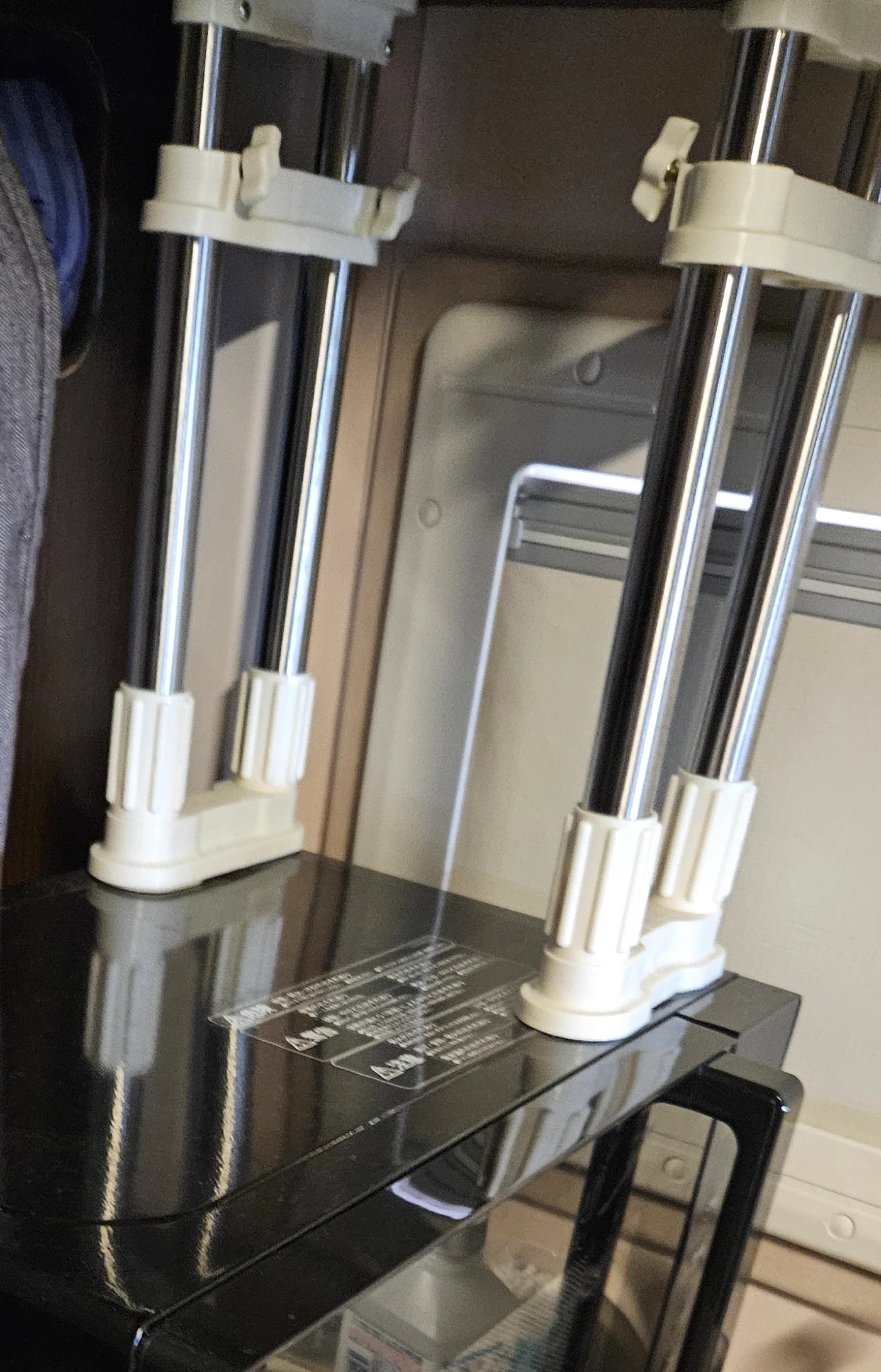 車内の電子レンジの上に取り付けた2本のBAOYOUNI家具転倒防止伸縮棒。上下の固定部分と支柱